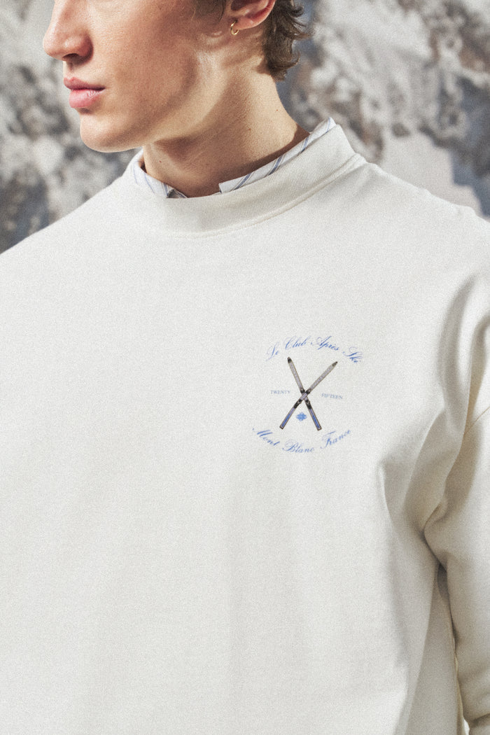 Person wearing a light t-shirt with a logo on a textured wall background