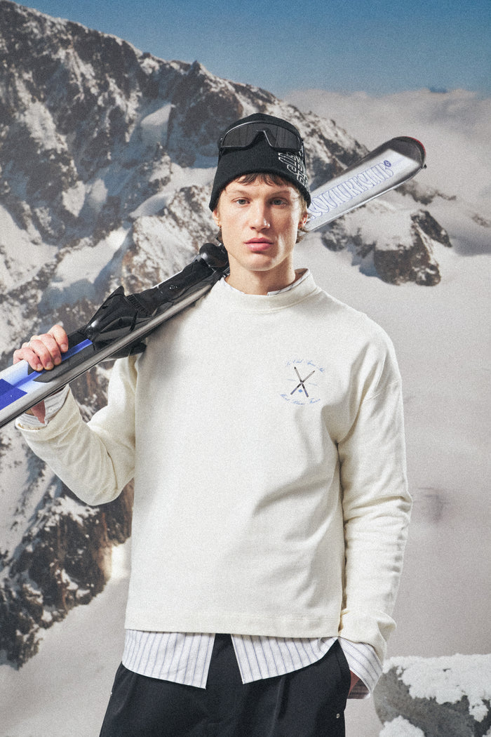 Person holding skis against a snowy mountain background