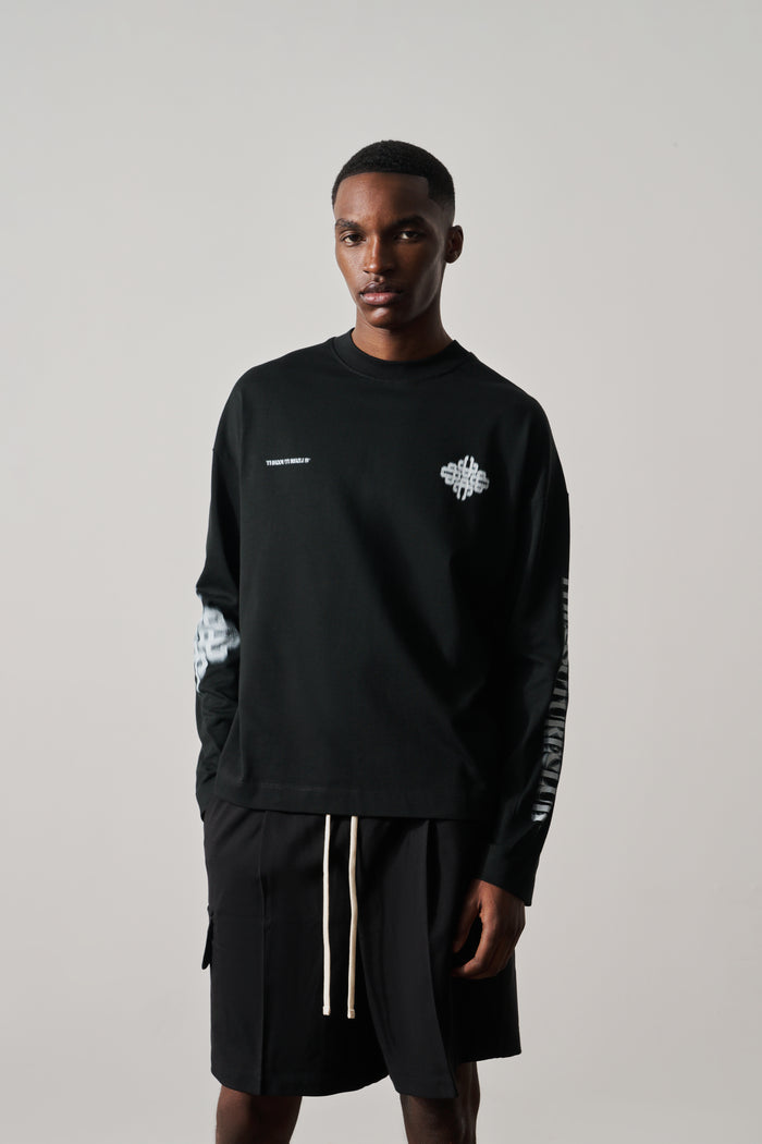 Man wearing a black long-sleeved t-shirt with white graphics on a plain background