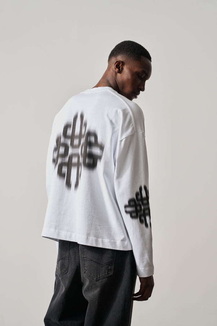 Person wearing a white long-sleeve t-shirt with black text design on a plain background
