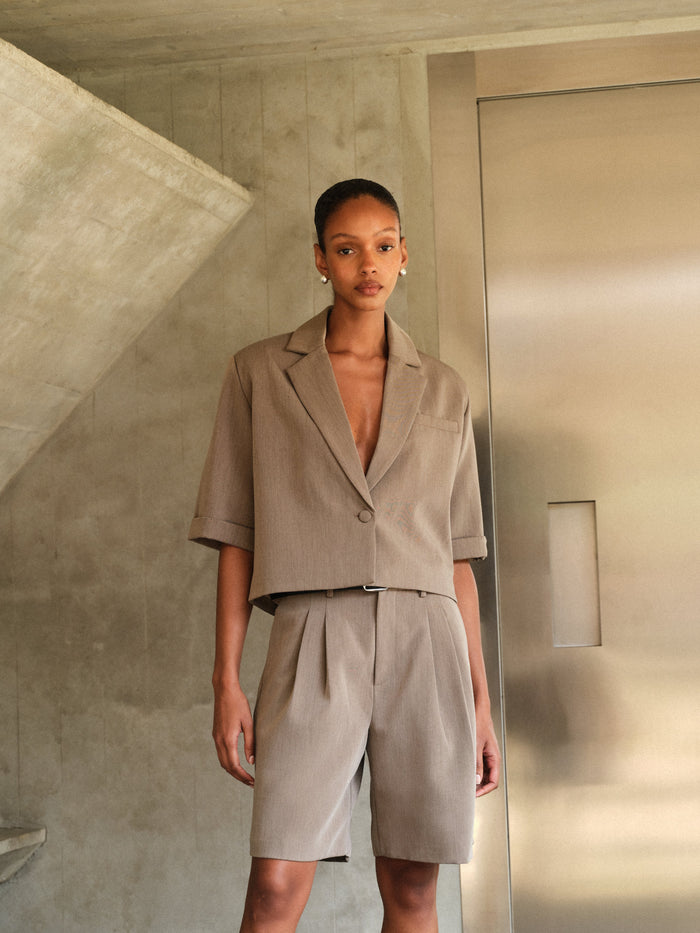 Woman wearing a beige tailored suit standing in a modern interior setting